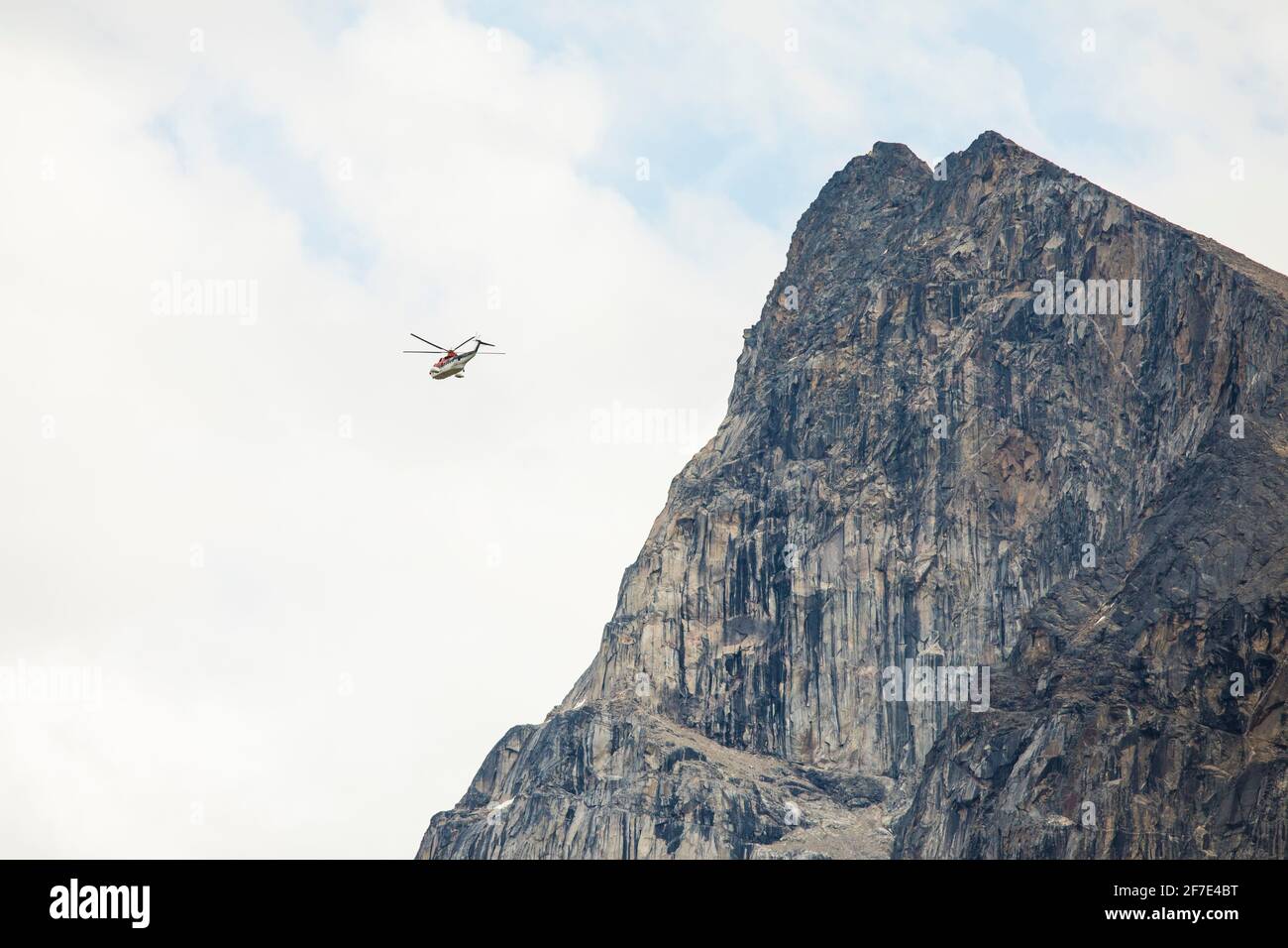Hubschrauber fliegt neben einer Bergklippe. Stockfoto