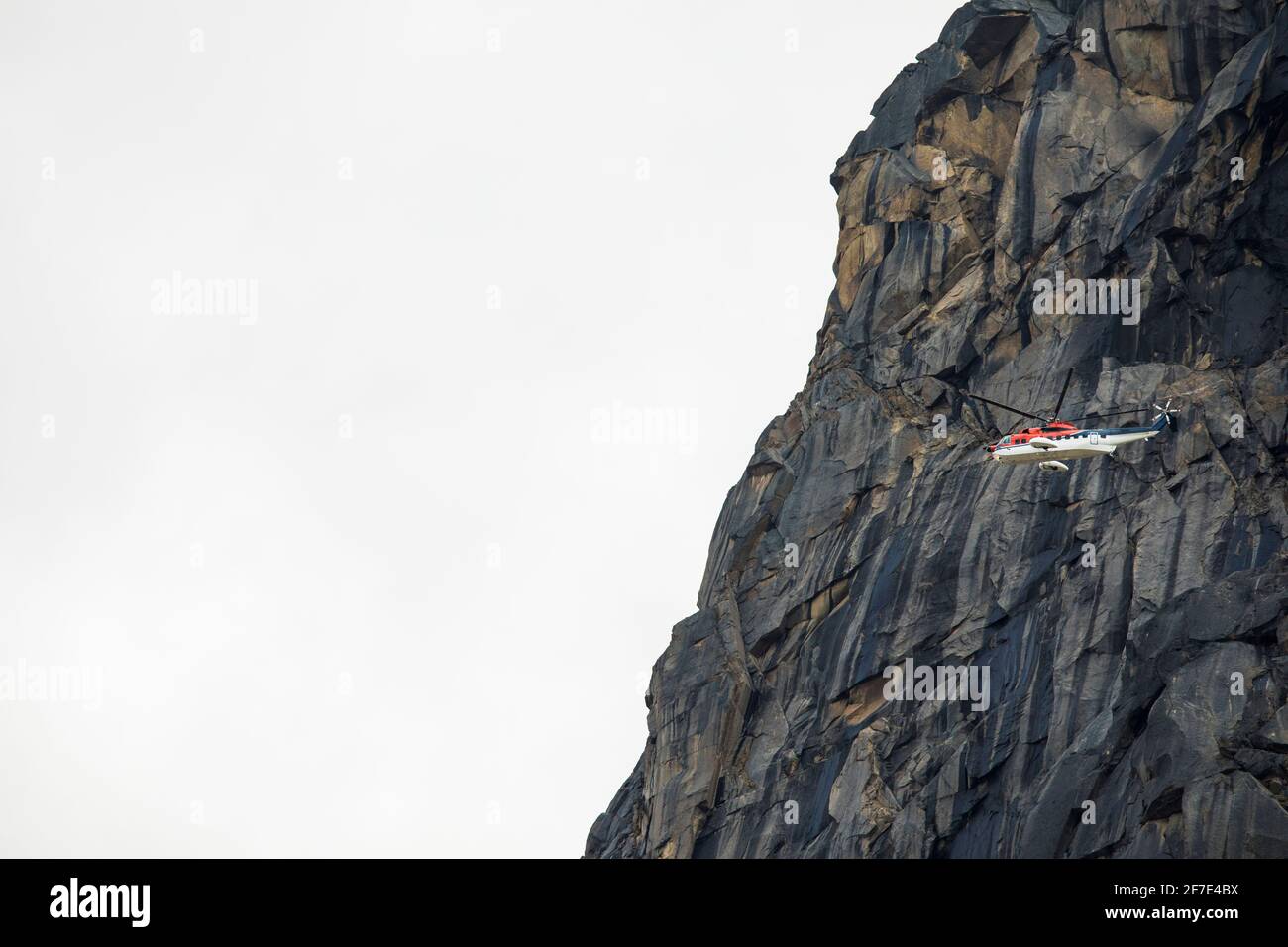 Hubschrauber fliegt neben einer Bergklippe auf Baffin Island Stockfoto