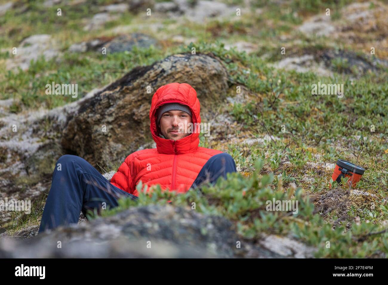 Porträt eines Bergsteigers in einer roten Daunenjacke. Stockfoto