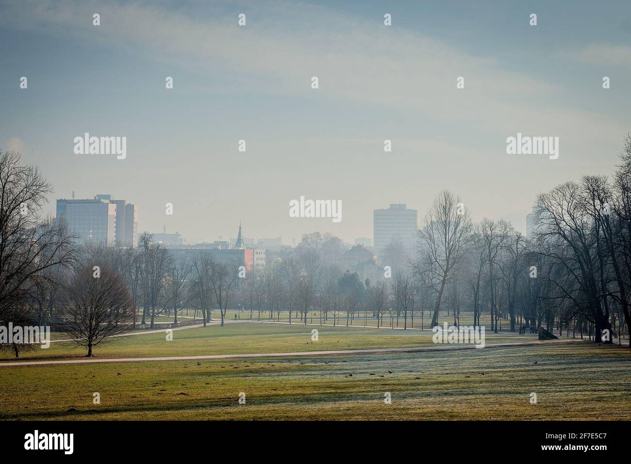 Neblige morgendliche Winterlandschaft der Stadt Ljubljana, vom nahegelegenen Tivoli Park aus gesehen. Satte grüne Felder mit einer Stadt im Hintergrund. Stockfoto