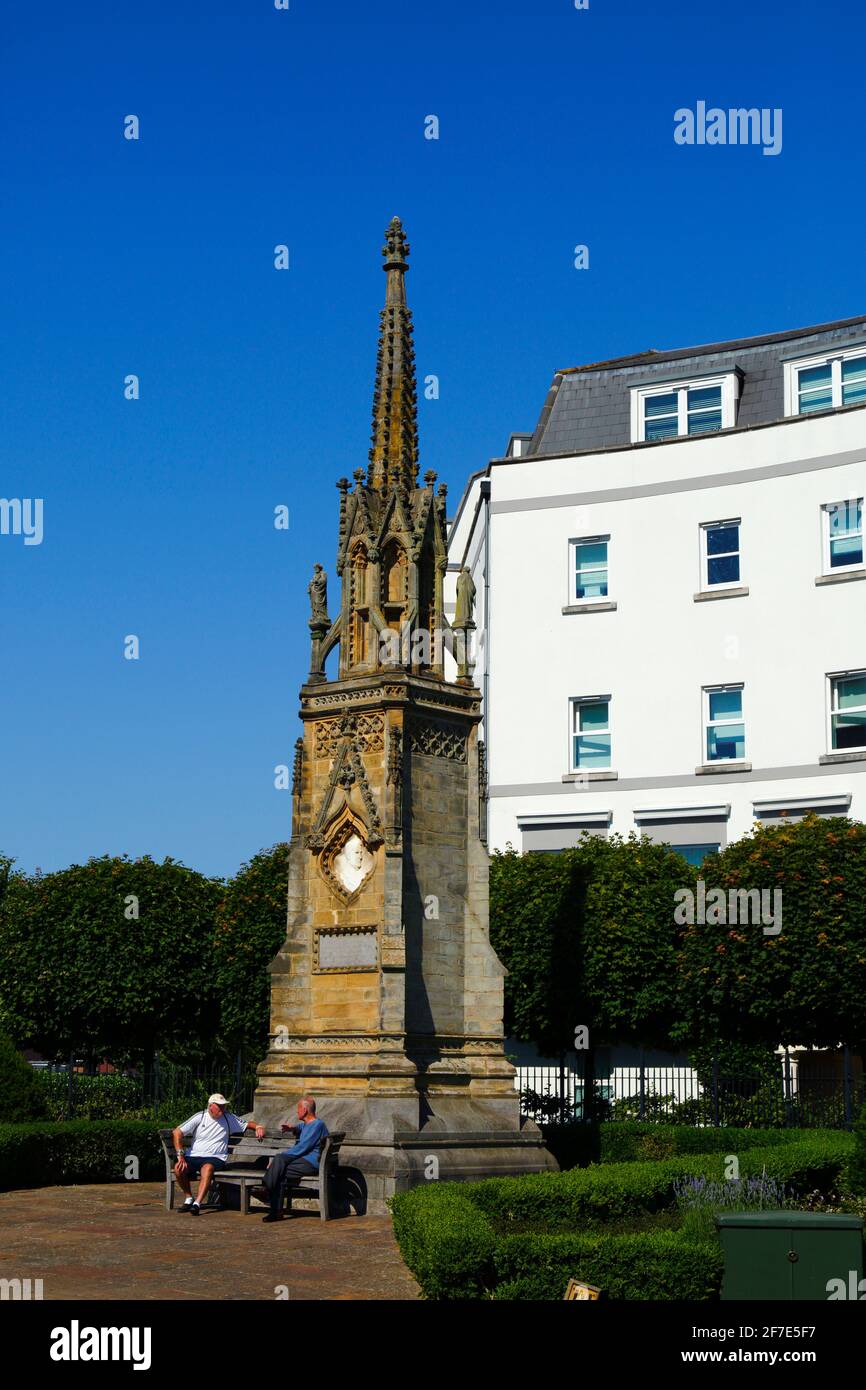 Männer sitzen auf einer Bank vor dem Edward Hoare-Denkmal an der Ecke von Culverden Park und St John's Road, Royal Tunbridge Wells, Kent, England Stockfoto