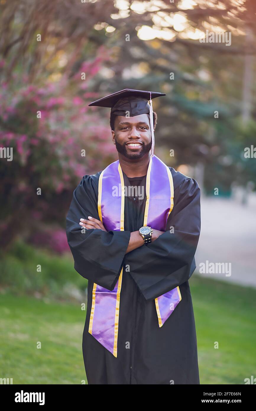 Junger Mann, der ein Abschlusskleid/eine Abschlusskappe trägt Stockfoto