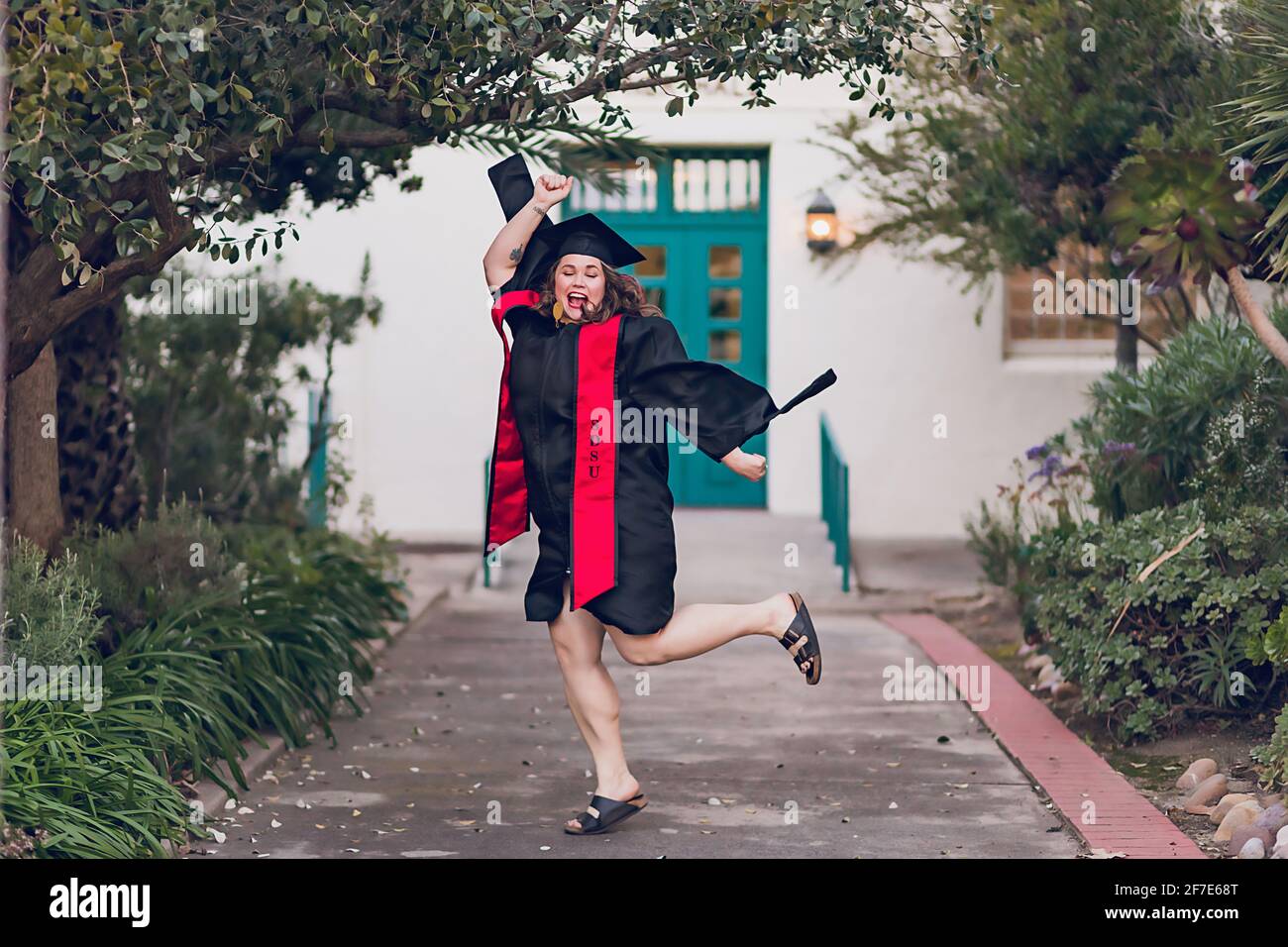 Frau freut sich, das College zu schließen, trägt ein Abschlusskleid/Mütze. Stockfoto
