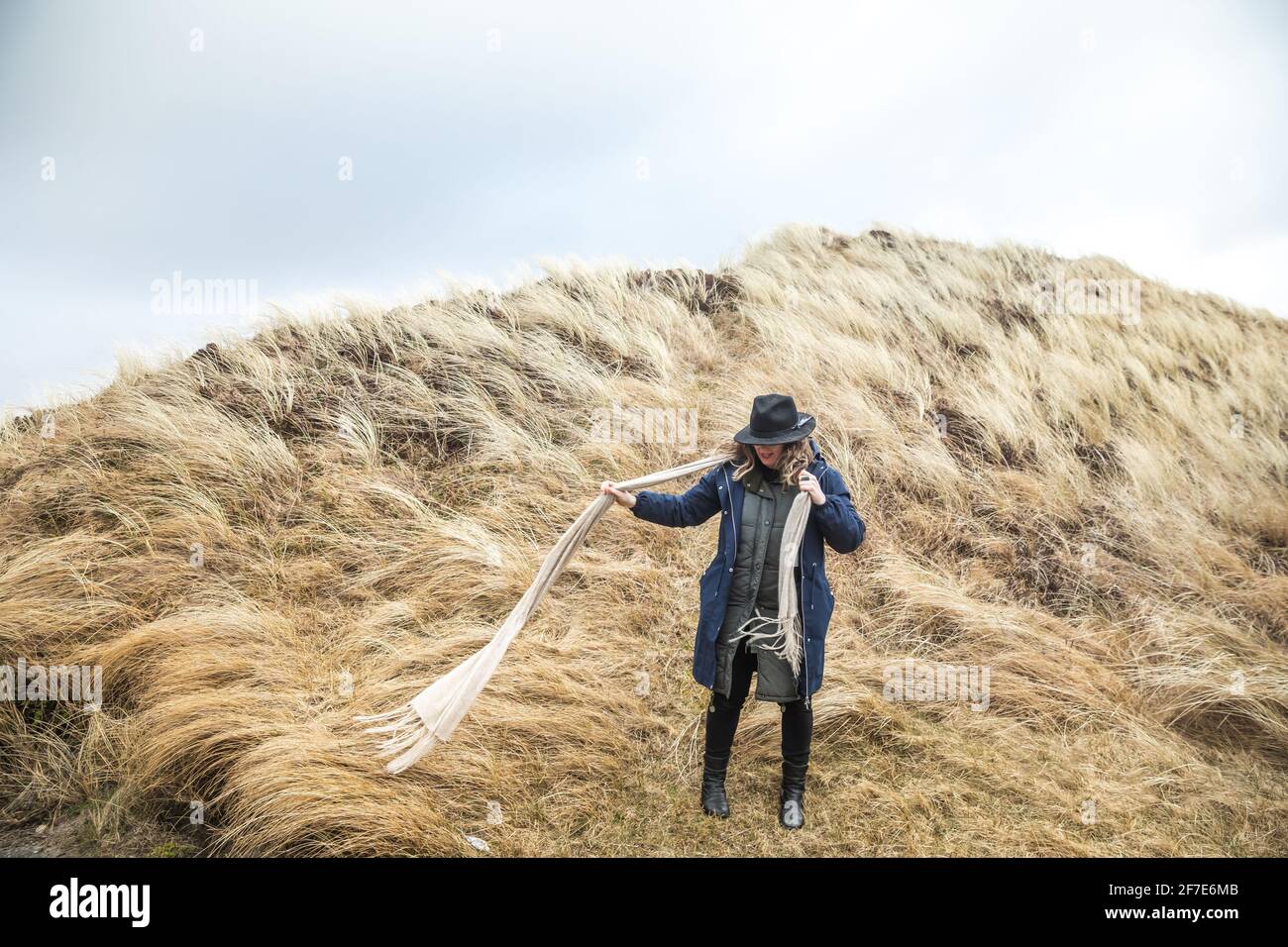 Frau mit langem Schal im Seegras auf einem windigen Tag in Dänemark Stockfoto