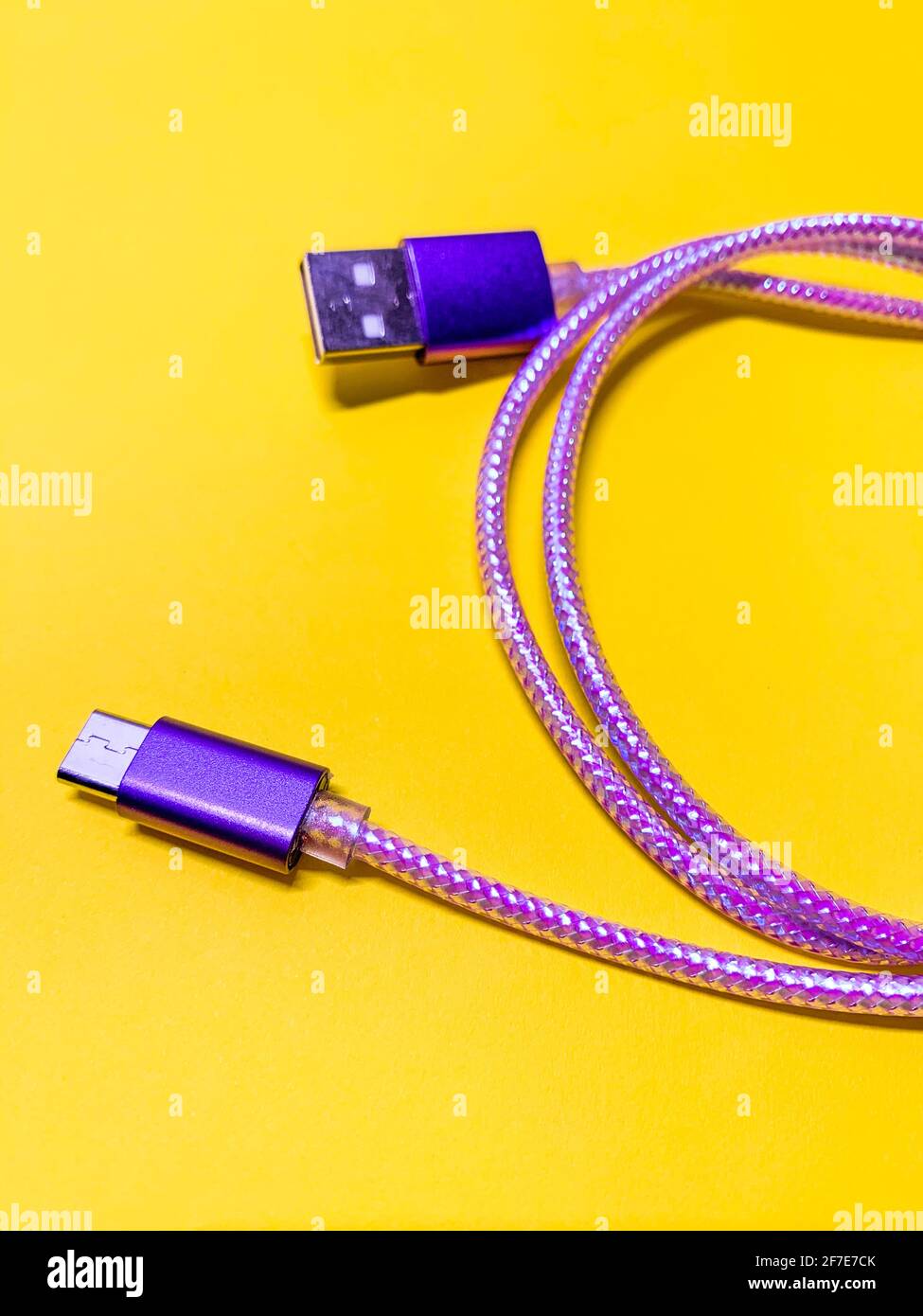 Nahaufnahme des violetten usb-Kabels auf gelbem Hintergrund, vertikale Ausrichtung Stockfoto