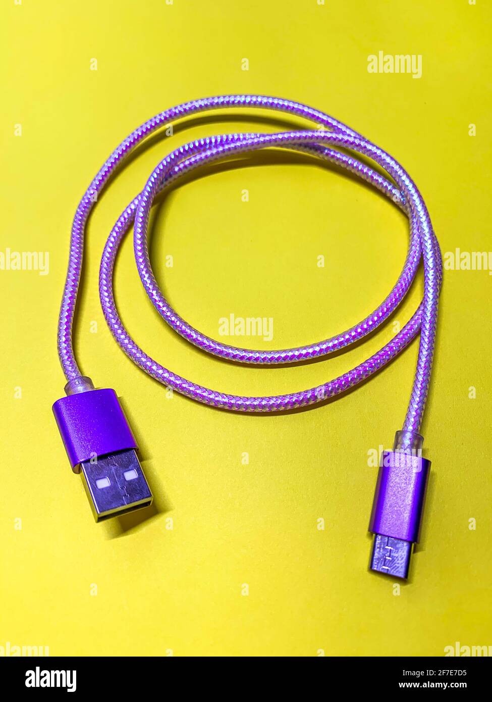 Violettes usb-Kabel auf gelbem Hintergrund, vertikale Ausrichtung Stockfoto