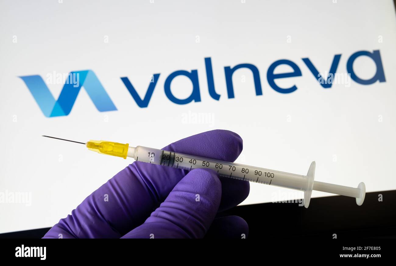 Valneva COVID-19 Impfstoffkonzept. Spritze und Valneva Firmenlogo auf dem unscharfen Hintergrundbildschirm. Stafford, Großbritannien, 6. April 2021. Stockfoto