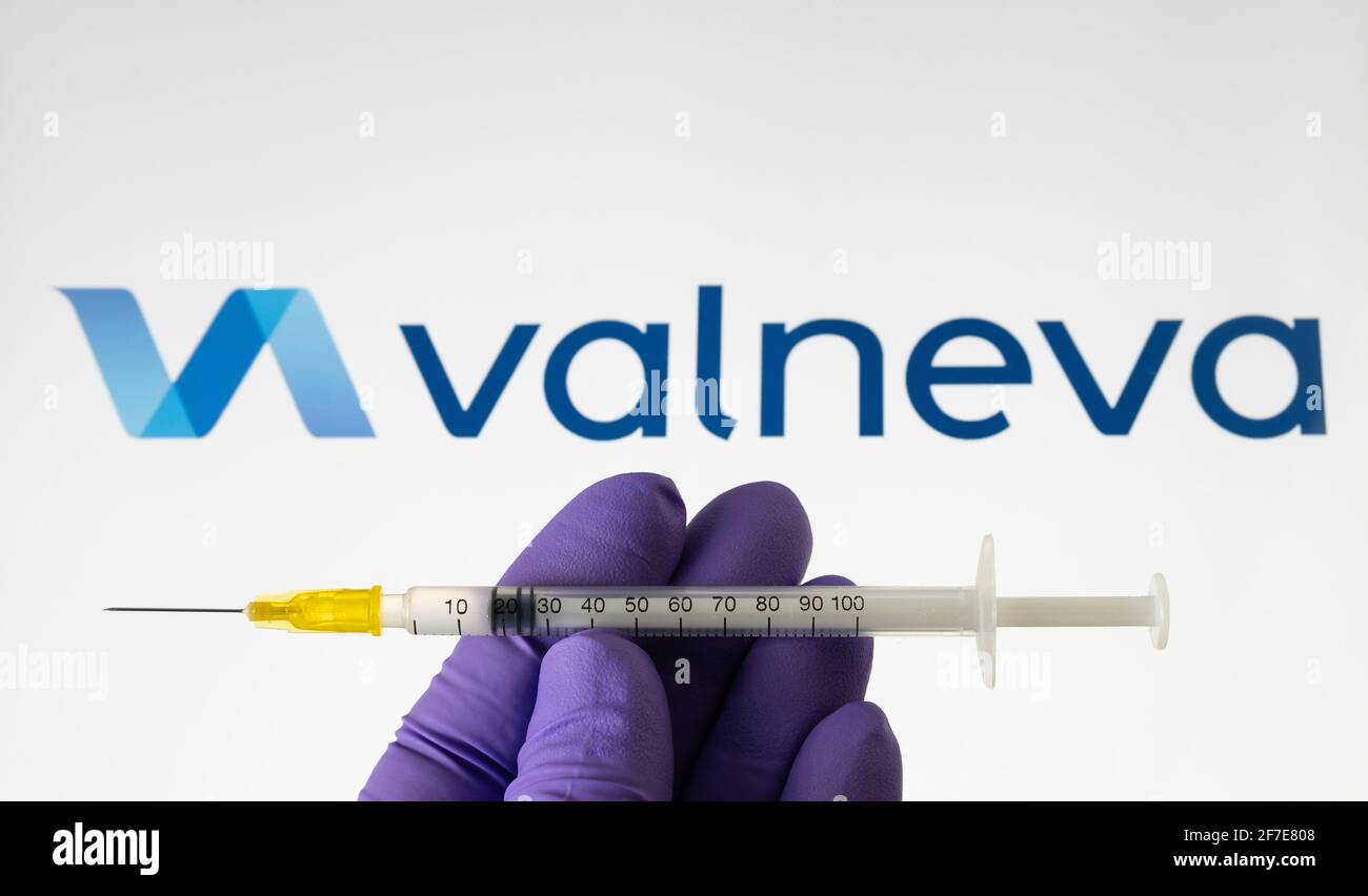 Valneva COVID-19 Impfstoffkonzept. Spritze und Valneva Firmenlogo auf dem unscharfen Hintergrundbildschirm. Stafford, Großbritannien, 6. April 2021. Stockfoto