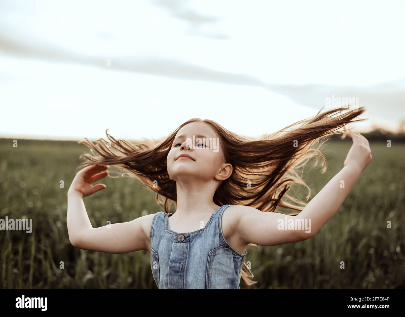 Wind im Haar. Porträt eines 5-jährigen Mädchens bei Sonnenuntergang mit Fliegen Stockfoto