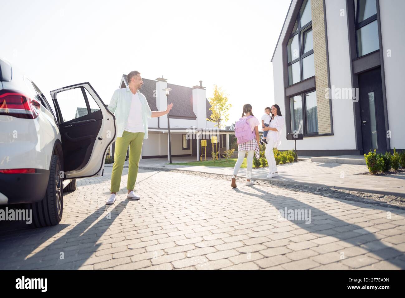 Foto in voller Größe von glücklich lächelnden Tochter der Familie kommen zurück Von der Schule trafen Mutter und kleiner Sohn sie draußen Stockfoto