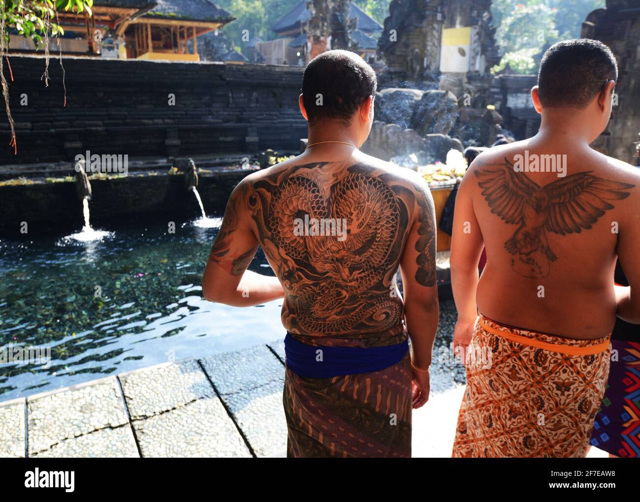 Tätowierte balinesische Männer, die bereit sind, den reinigenden Pool am Tirta Empul Tempel in Bali, Indonesien, zu betreten. Stockfoto