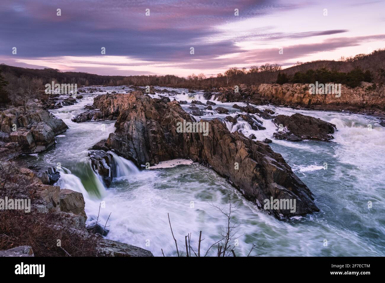 Winter lila Wolken bei Sonnenuntergang über dem Potomac River und Great Falls Park in Virginia. Stockfoto