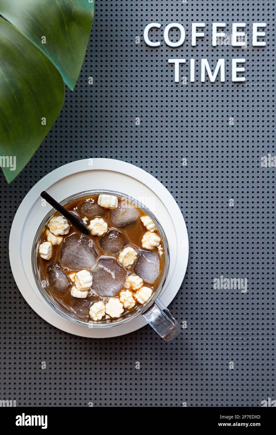 Sommer Zusammensetzung von Eiskaffee Tasse mit Marshallows. „Coffee Time“-Wort und Monstera-Palmblatt mit Tasse Kaffee. Modernes Posterlayout. Stockfoto