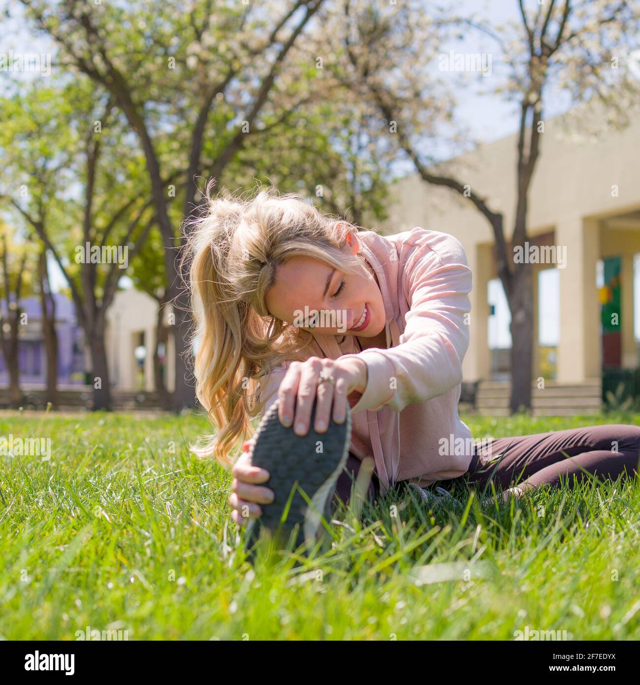 Junge Frau, die sich vor dem Laufen im Park dehnt Stockfoto