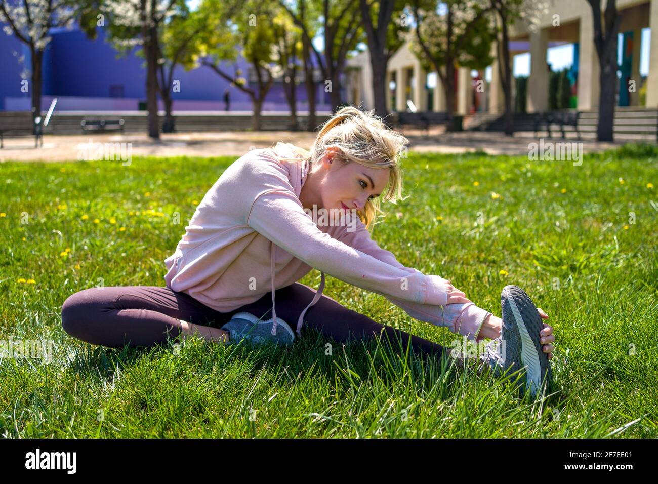 Junge Frau, die sich vor dem Laufen im Park dehnt Stockfoto