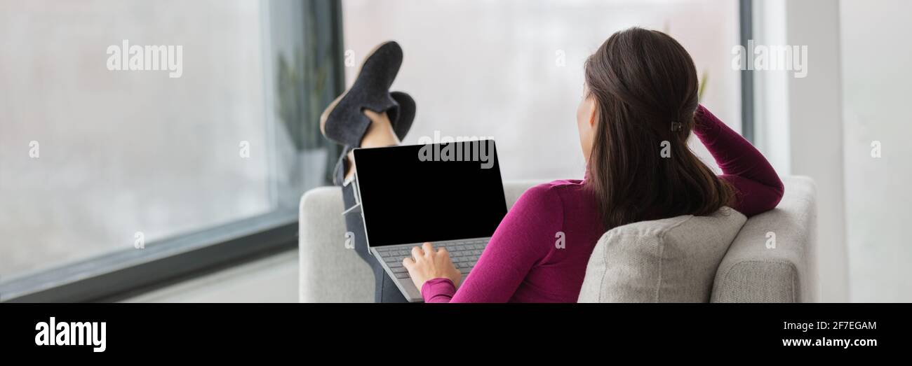 Student zu Hause Remote-Arbeit, der sich virtuelle Webinar-Videocall im Online-Kurs ansieht. Frau von hinten entspannt die Füße auf dem Sofa im Wohnzimmer, einfaches Lernen Stockfoto