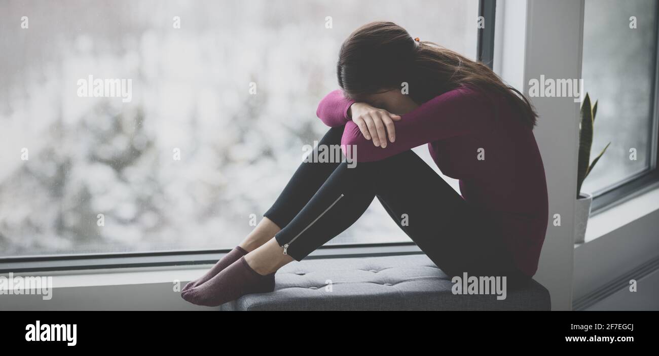 Traurige weinende junge Frau, die sich in Traurigkeit allein zu Hause in Isolation versteckt. Psychische Gesundheit Problem soziale Angst Panikattacke ptsd Auswirkungen von der Stockfoto