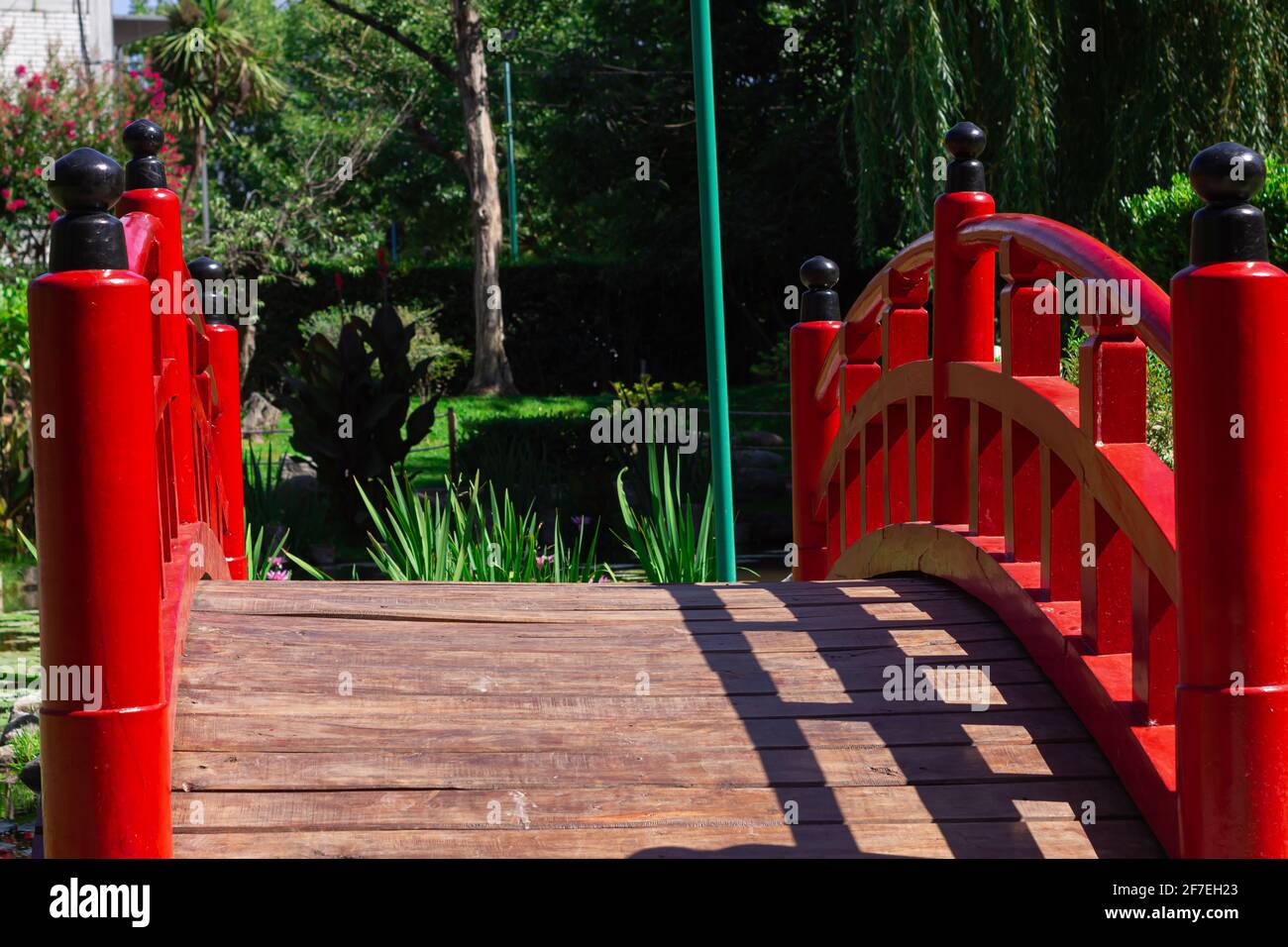 Kleine rote Brücke in einem Stadtpark an einem sonnigen Tag. Stockfoto