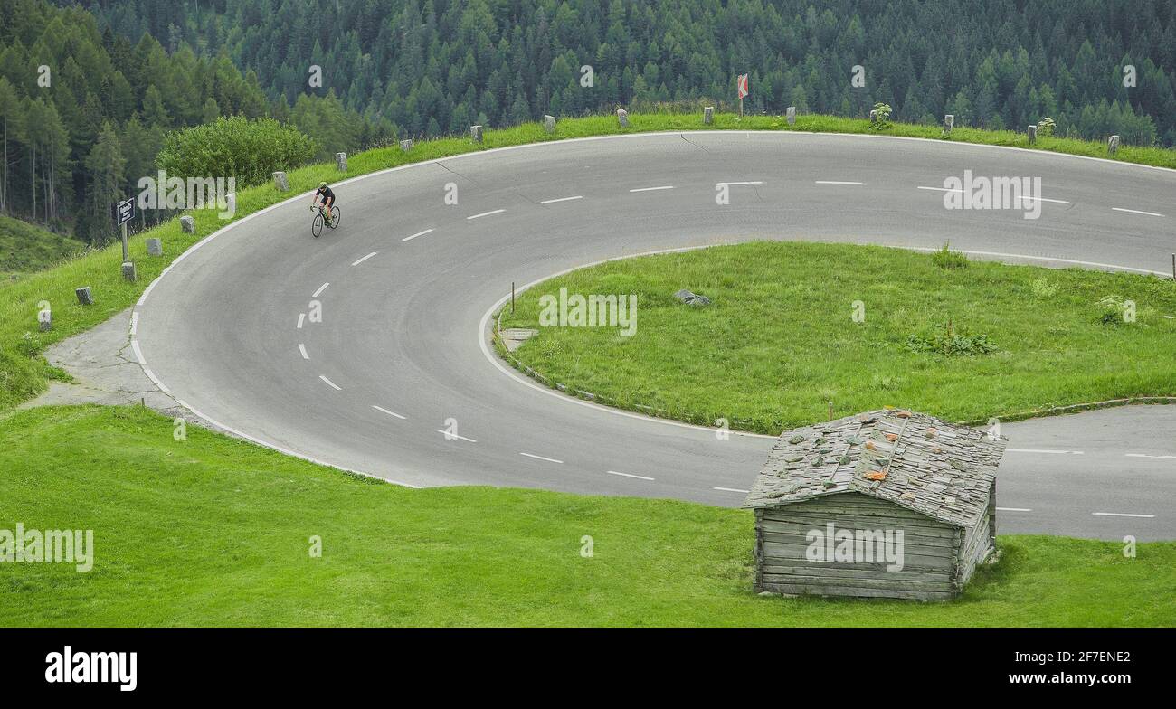 Einzelradfahrer, die auf einer kurvigen Straße mit Serpentinen oder Haarnadelkurve bergauf fahren, während sie zum Großglockner, Hochgebirgspass in Österreich, klettern Stockfoto