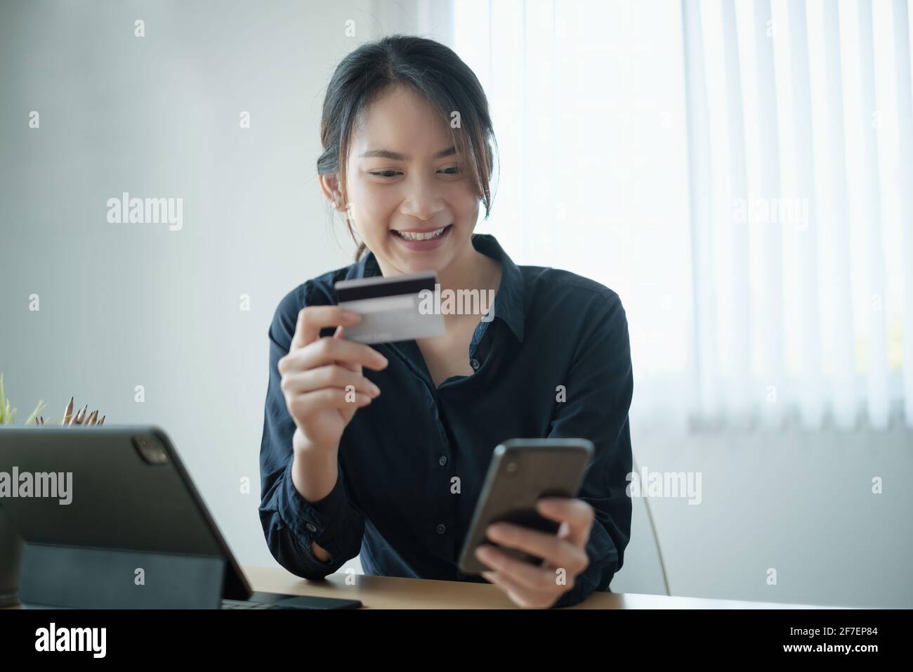 Frau im legeren Hemd, die online mit Kreditkarte bezahlt, während sie Bestellungen über die Anwendung auf dem Handy macht. Erfolgreiche und glückliche Geschäftsfrau machen Stockfoto