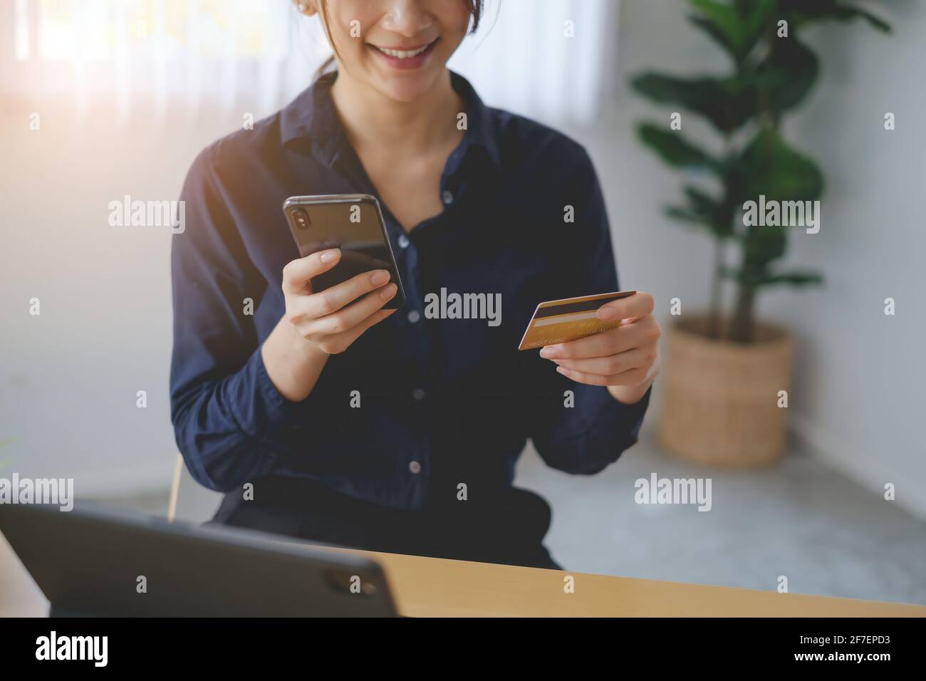 Frau im legeren Hemd, die online mit Kreditkarte bezahlt, während sie Bestellungen über die Anwendung auf dem Handy macht. Erfolgreiche und glückliche Geschäftsfrau machen Stockfoto