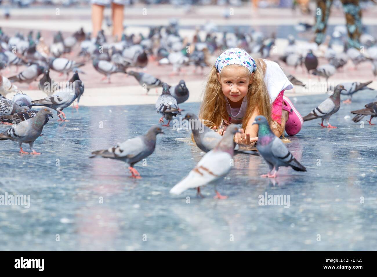 Ein Mädchen im Alter von 6-7 Jahren, das Tauben auf der Plaza de Catalunya in Barcelona füttert. Stockfoto
