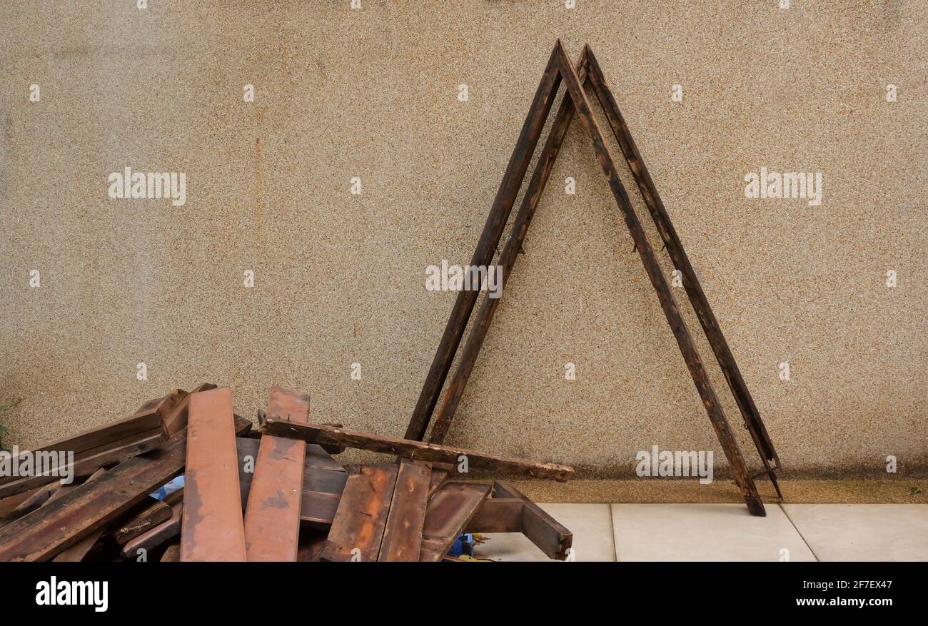 Nahaufnahme und Fokus auf beschädigte V-förmige Holzplanken, die sich anlehnen Die Wand nach dem Abriss Stockfoto