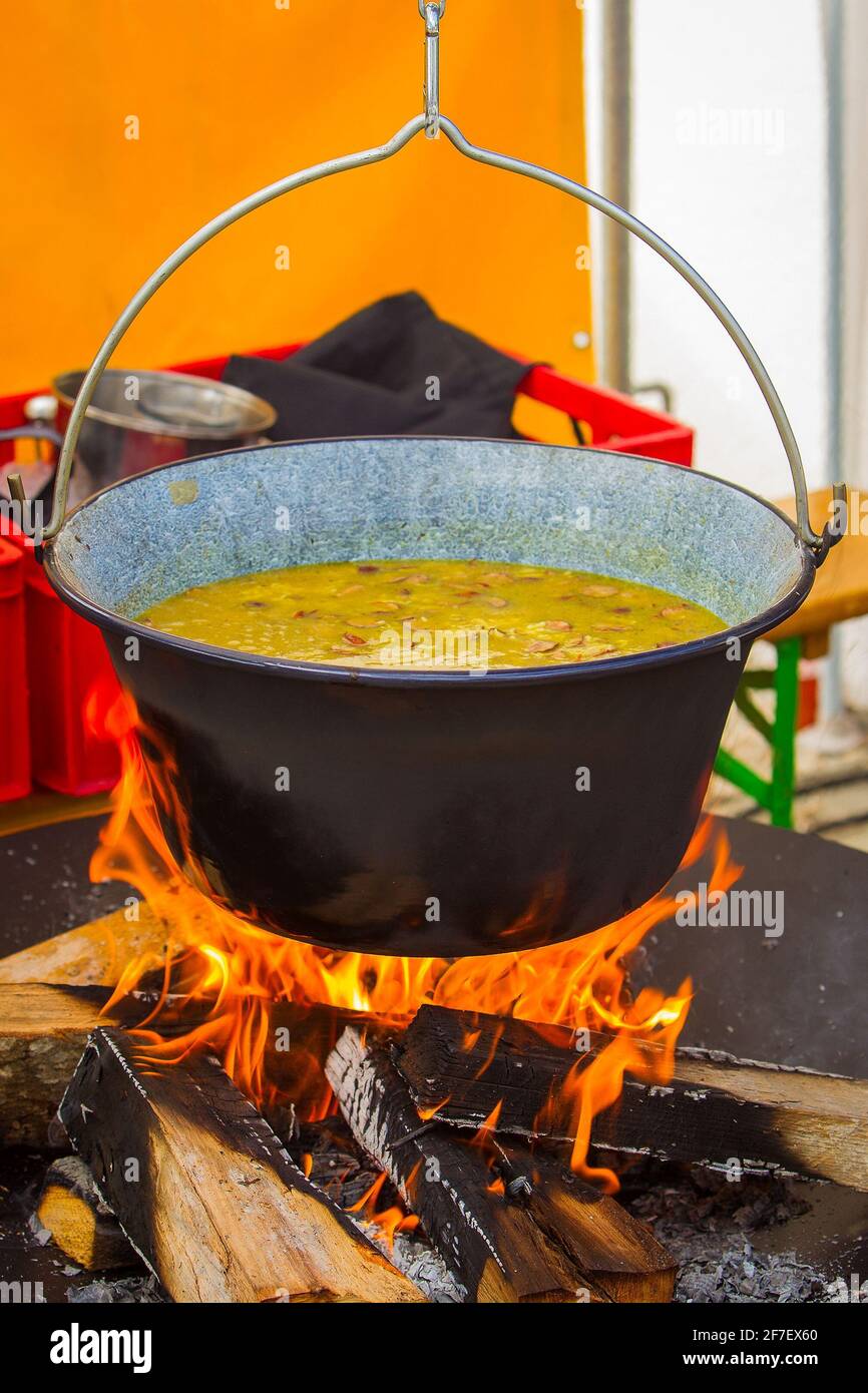 Ein Eintopf oder eine Suppe wird in einer Schüssel über einem offenen Feuer zubereitet. Stockfoto