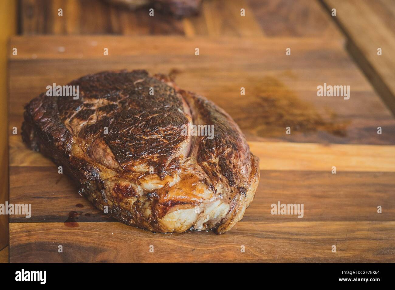 Ein großes Stück Rindersteak, das auf einem Holztisch in kleinere Stücke geschnitten werden kann. Stockfoto