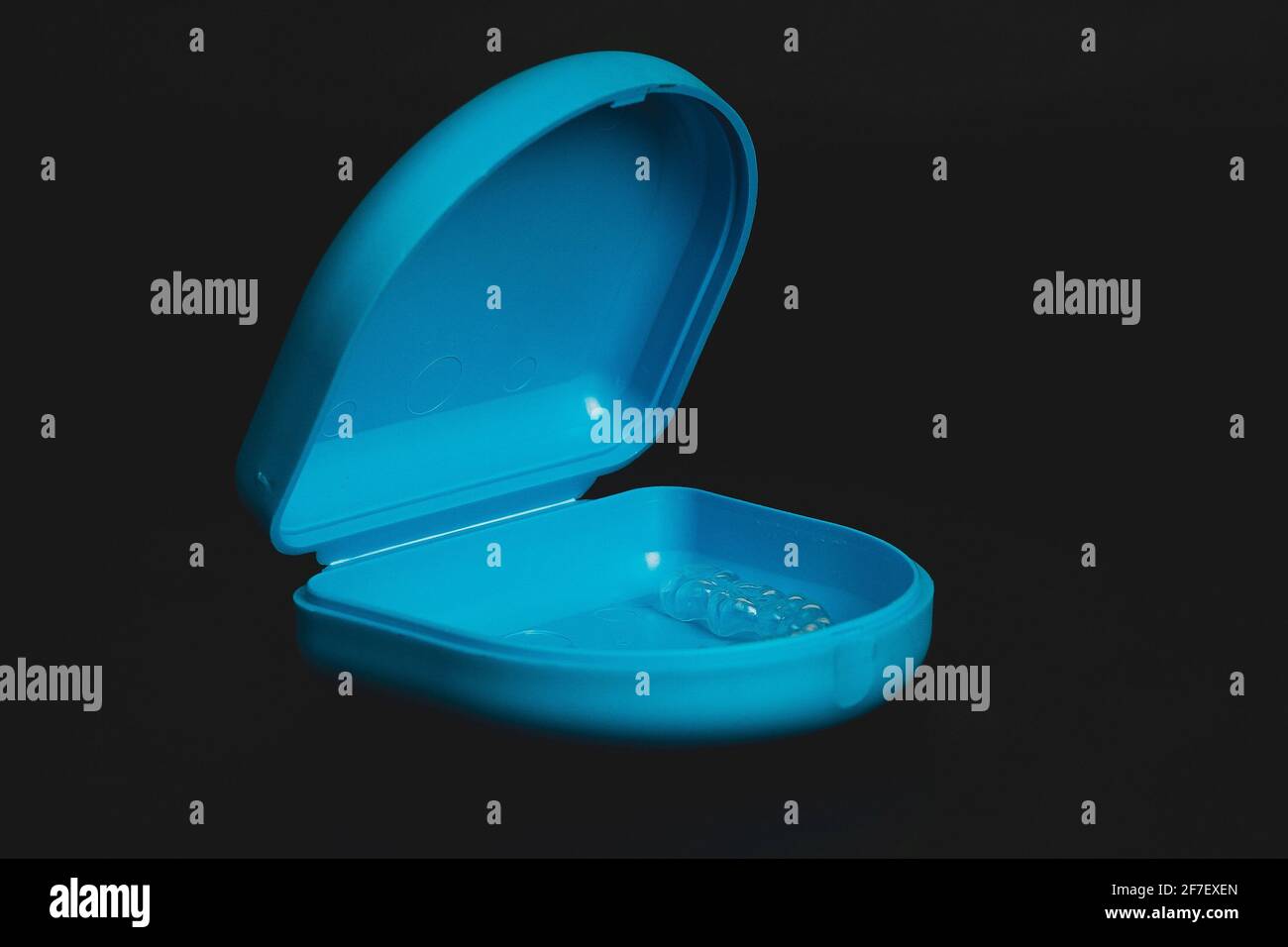 Blaue Tragetasche für kieferorthopädische Halterung aus transparentem Kunststoff, isoliert auf schwarz. Halter zum Ausrichten der Zähne. Stockfoto
