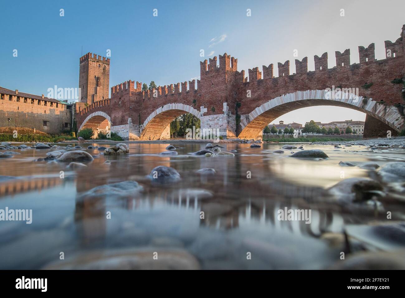 Low-Profile Langzeitaufnahme einer Brücke des Castel vecchio in Verona, Italien an einem sonnigen Tag. Schöne Ziegelmauer über dem Fluss Etsch auf einem blauen sk Stockfoto