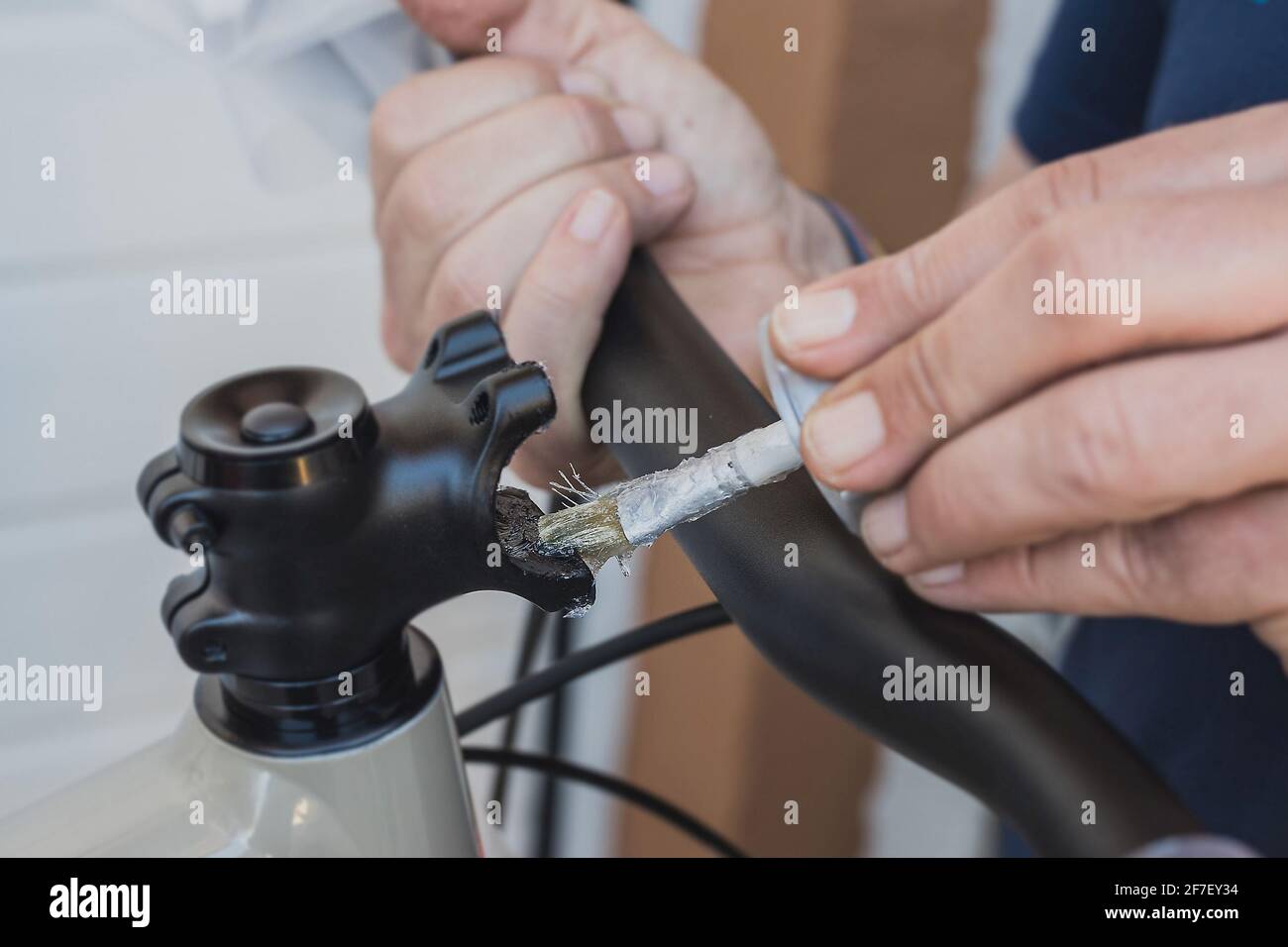 Schmieren eines Fahrradlenkervorbaus mit einem kleinen Pinsel. Richtige Art und Weise, einen Fahrradlenker zu installieren. Fahrradservice in einer Werkstatt. Stockfoto