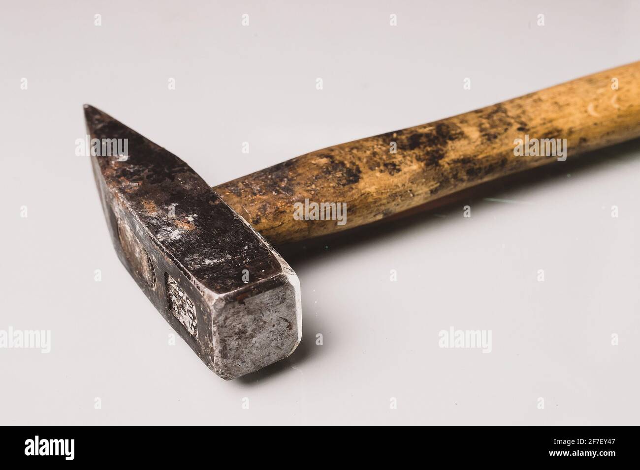 Ein gebrauchter und abgenutzter hammer im europäischen Stil mit Holzgriff und Metallspitze. Isoliert auf weißer reflektierender Platine. Stockfoto