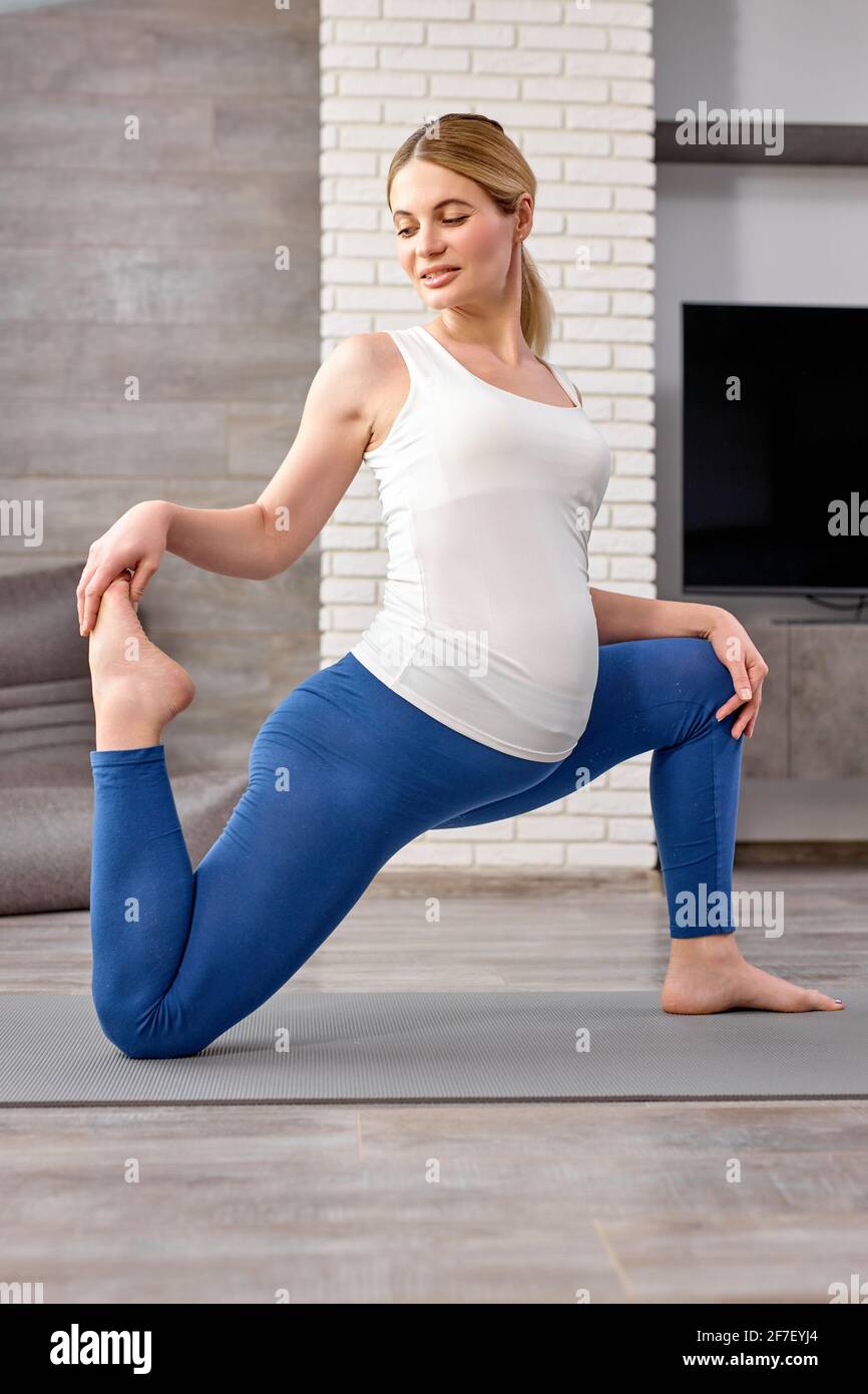 Flexible Schwangere Frau in Sportbekleidung beschäftigt Training zu Hause, strecken den Körper, trainieren Körpermuskeln. Wellness, gesunde Lebensweise, Sport, Yoga, stret Stockfoto