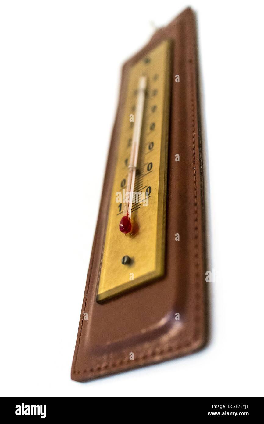 Innenthermometer mit Alkohol im Vintage-Stil in Ledergehäuse, an einer Wand montiert. Bild aus einer niedrigen Perspektive aufgenommen, Fokus auf roten Alkoholbehälter. Stockfoto