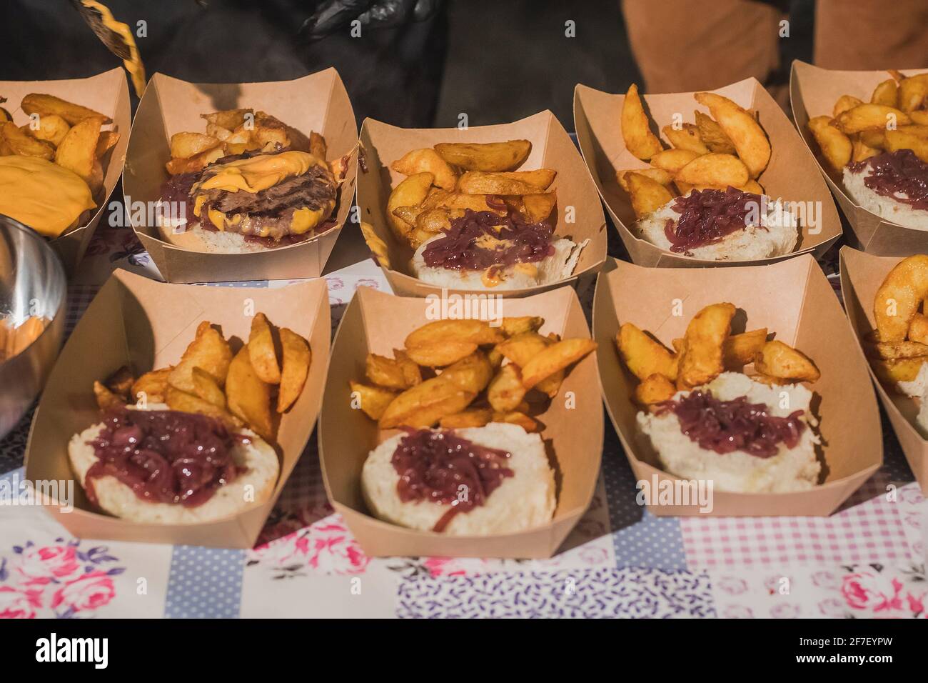 Zubereitung von Gourmet-Burgern oder Hamburgern mit Kartoffeln, Speck, Käse, Brötchen. Detail von halbgemachten Burgern in Pappkartons Stockfoto