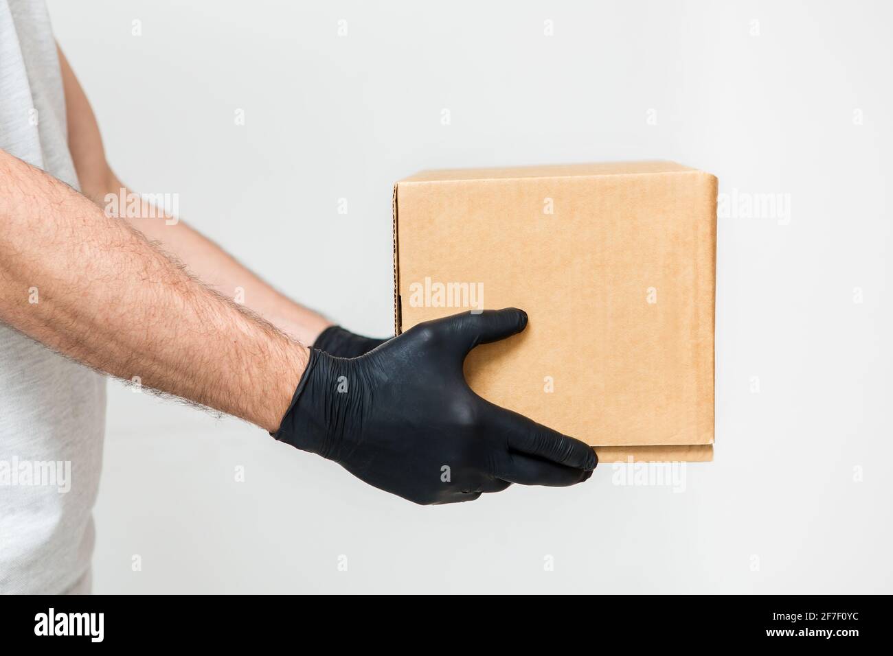 Kurierhände in medizinischen Gummihandschuhen, die Kartons halten. Lieferservice. Quarantäne. Coronavirus. Stockfoto