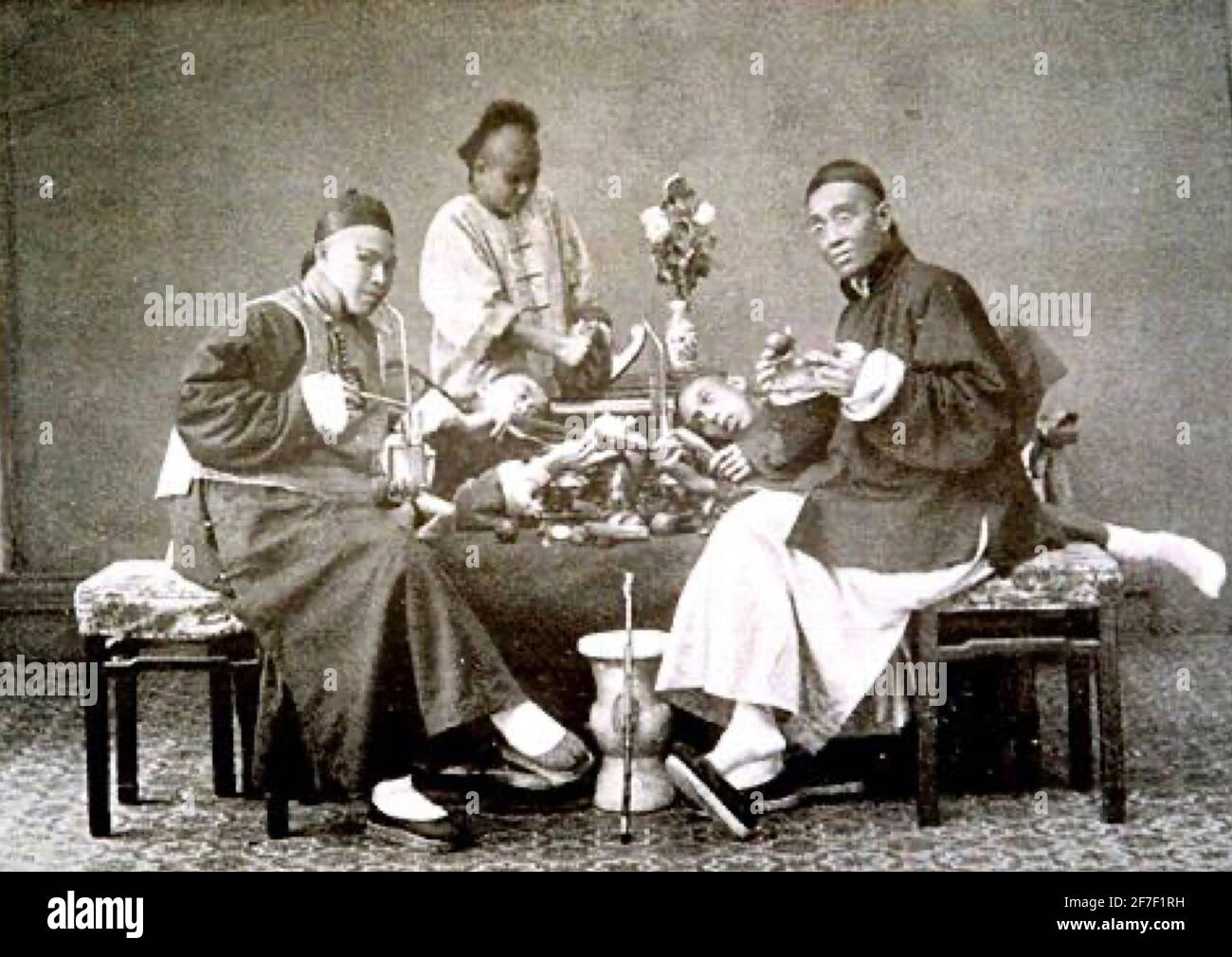 Frühes Foto von chinesischen Opiumrauchern. Zwei Erwachsene im Vordergrund und drei weitere jüngere Menschen, zwei, die bewusstlos zu sein scheinen. Stockfoto