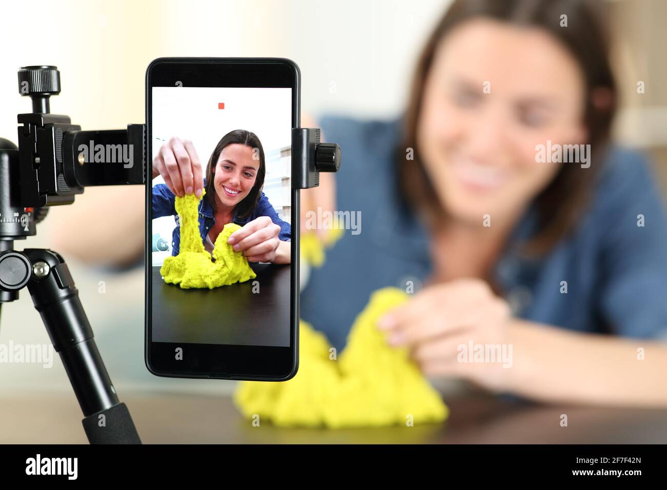Glücklicher Influencer, der Videos mit einem smaprt-Telefon aufzeichnet, das mit Cinetic spielt Sand zu Hause Stockfoto