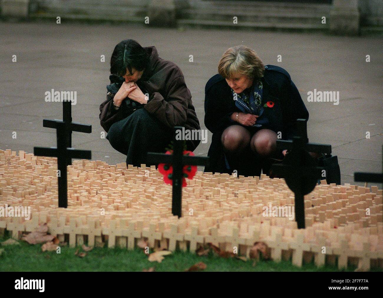 Nov 2000 W omen suchen nach Namen auf Kreuzen draußen In der Westminster Abbey sind Mohnblumen abgebildet Stockfoto