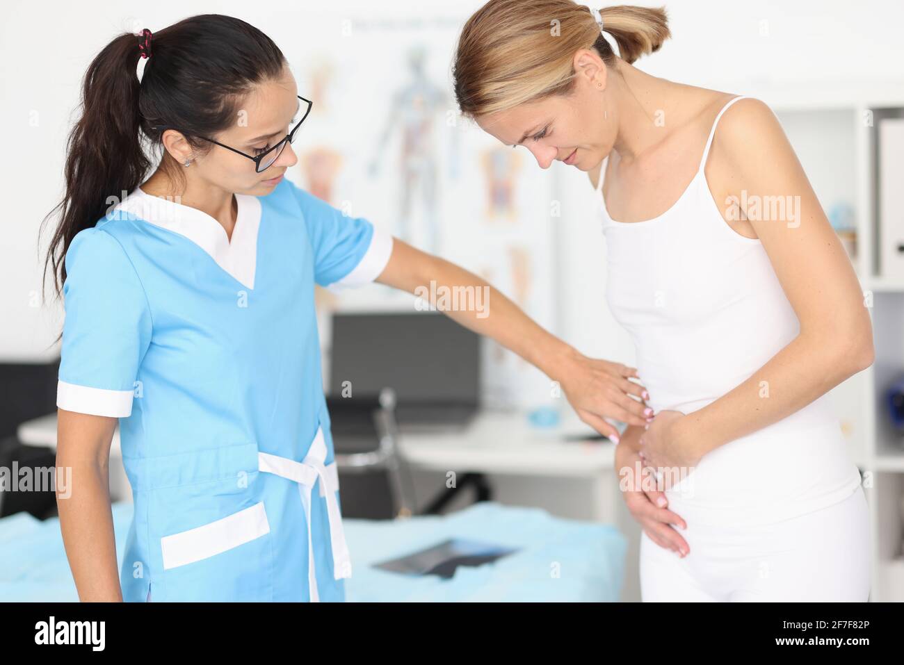 Der Arzt bietet der Frau mit Bauchschmerzen medizinische Hilfe an Stockfoto