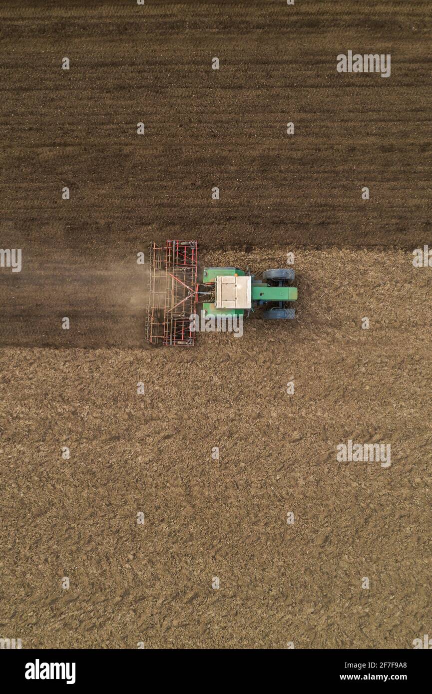 Luftaufnahme der landwirtschaftlichen Traktor Bodenbearbeitung und erschütternde gepflügten Feld, direkt über Drohne pov Bild von Maschinen arbeiten auf Ackerland Stockfoto