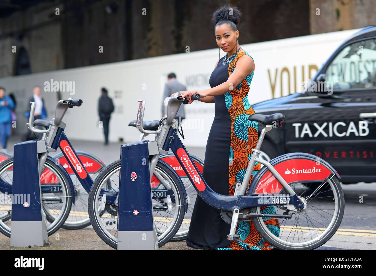 Mädchen mit bunten Kleid mit dem Santander Fahrrad mieten Scheme in London, Großbritannien Stockfoto