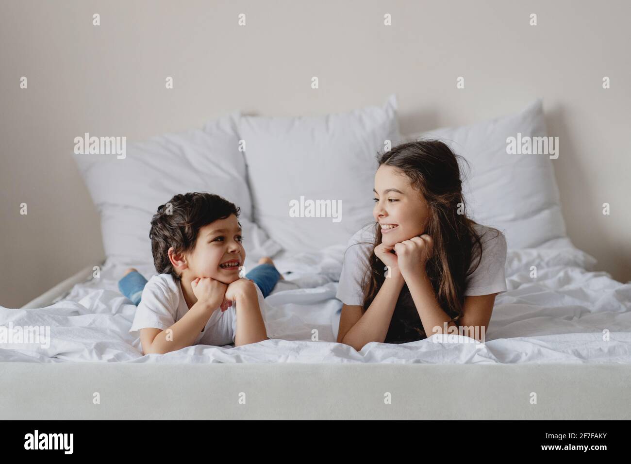 Bruder und Schwester schauten sich lächelnd auf dem Bett an und schauten sich an. Stockfoto