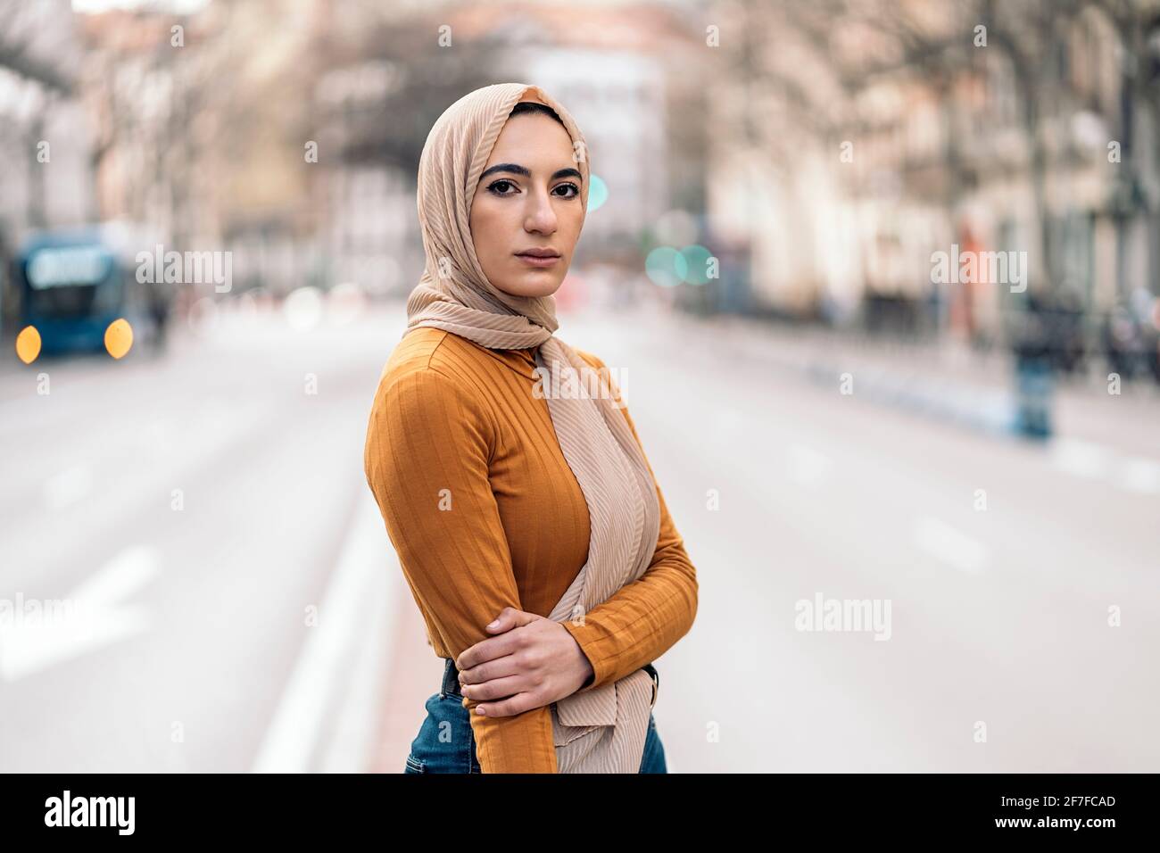 Schöne junge muslimische Frau, die in Hijab auf der Straße steht und die Kamera anschaut. Stockfoto