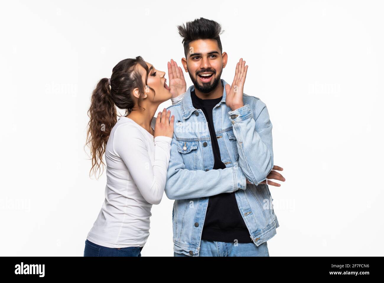 Porträt eines jungen indischen Paares, das Geheimnisse erzählt und zusammen steht Auf weißem Hintergrund Stockfoto