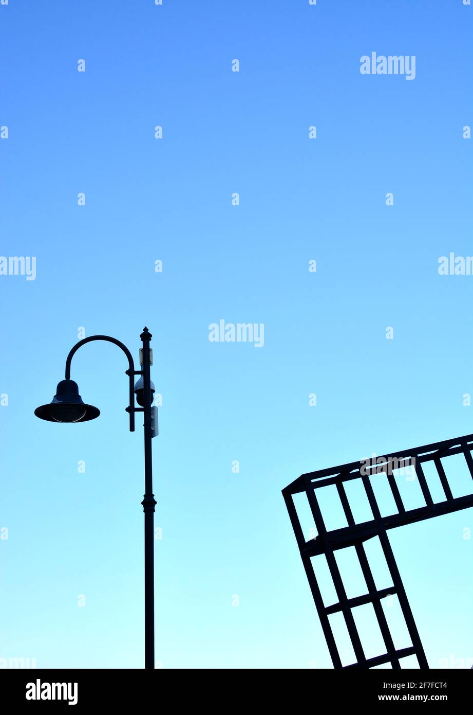 Eine Straßenlampe und ein Baurahmen vor dem Hintergrund Von einem klaren blauen Himmel Stockfoto