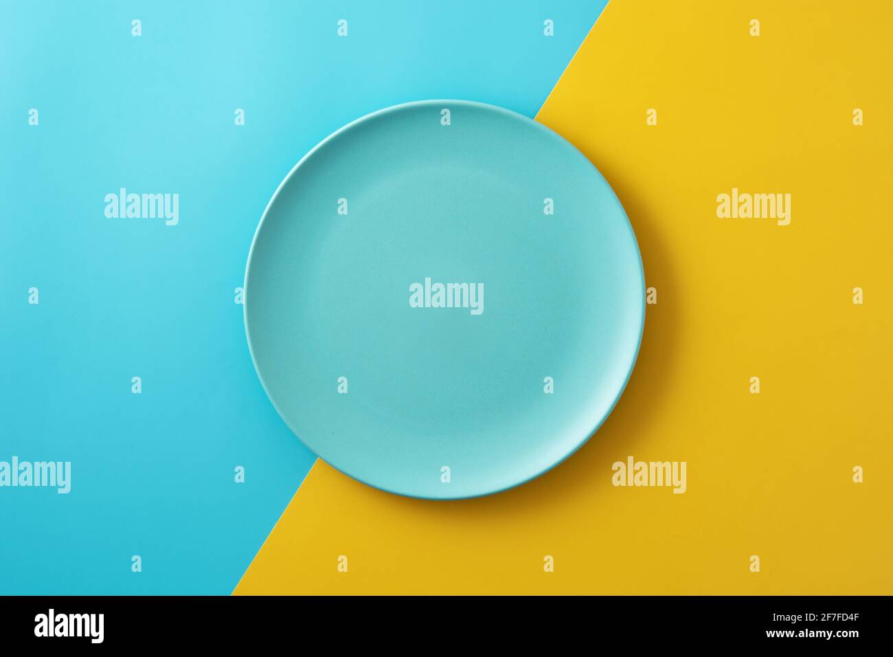 Leere blaue Platte auf gelbem und blauem Hintergrund Stockfoto