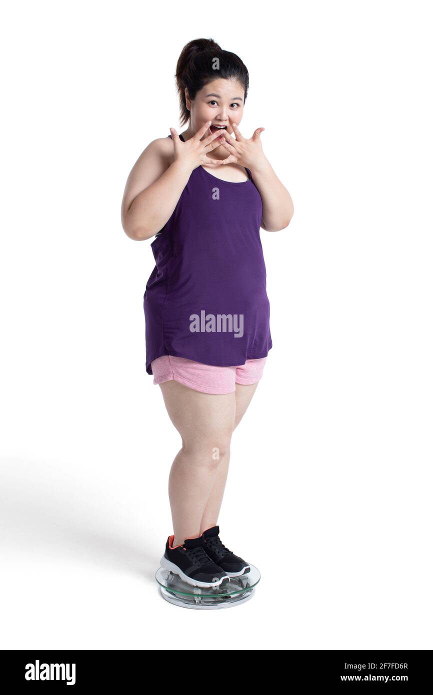 Übergewichtige junge Frau, die sich auf einer Waage wiegt Stockfoto