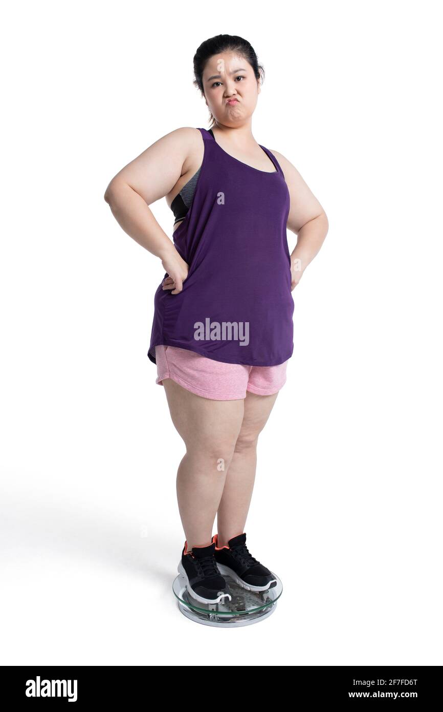 Übergewichtige junge Frau, die sich auf einer Waage wiegt Stockfoto